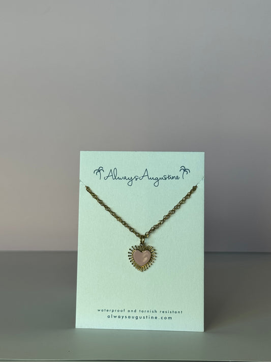 Necklace with heart pendant on a branded card against a plain background