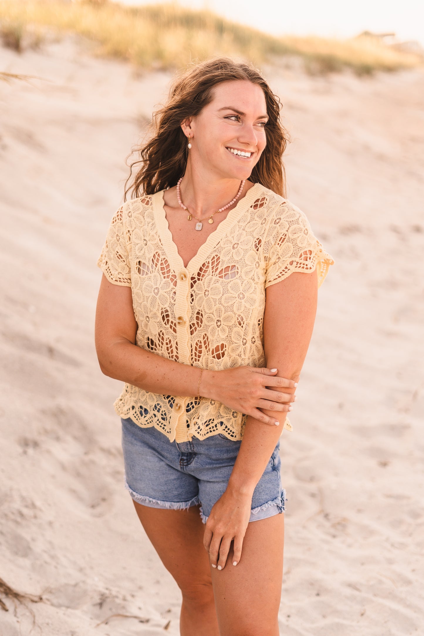 Model wearing the Malibu necklace featuring pink stabilized opal beads, a gold paperclip chain, and cowrie shell, palm tree, and scallop shell charms on waterproof 18k Gold PVD stainless steel components.