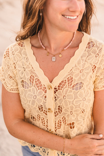 Model wearing the Malibu necklace featuring pink stabilized opal beads, a gold paperclip chain, and cowrie shell, palm tree, and scallop shell charms on waterproof 18k Gold PVD stainless steel components.
