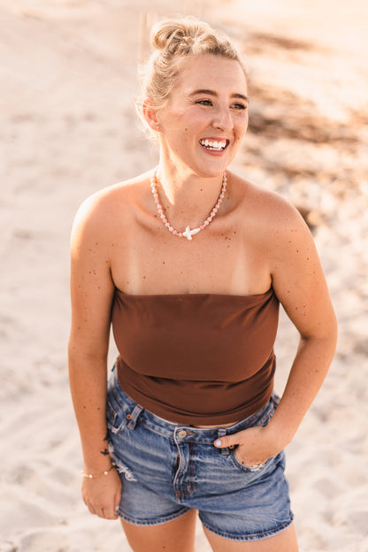 Model wearing the Blair necklace featuring pink stabilized opal beads, freshwater pearl spacers, and a freshwater pearl cross pendant on waterproof 18k Gold PVD stainless steel components.