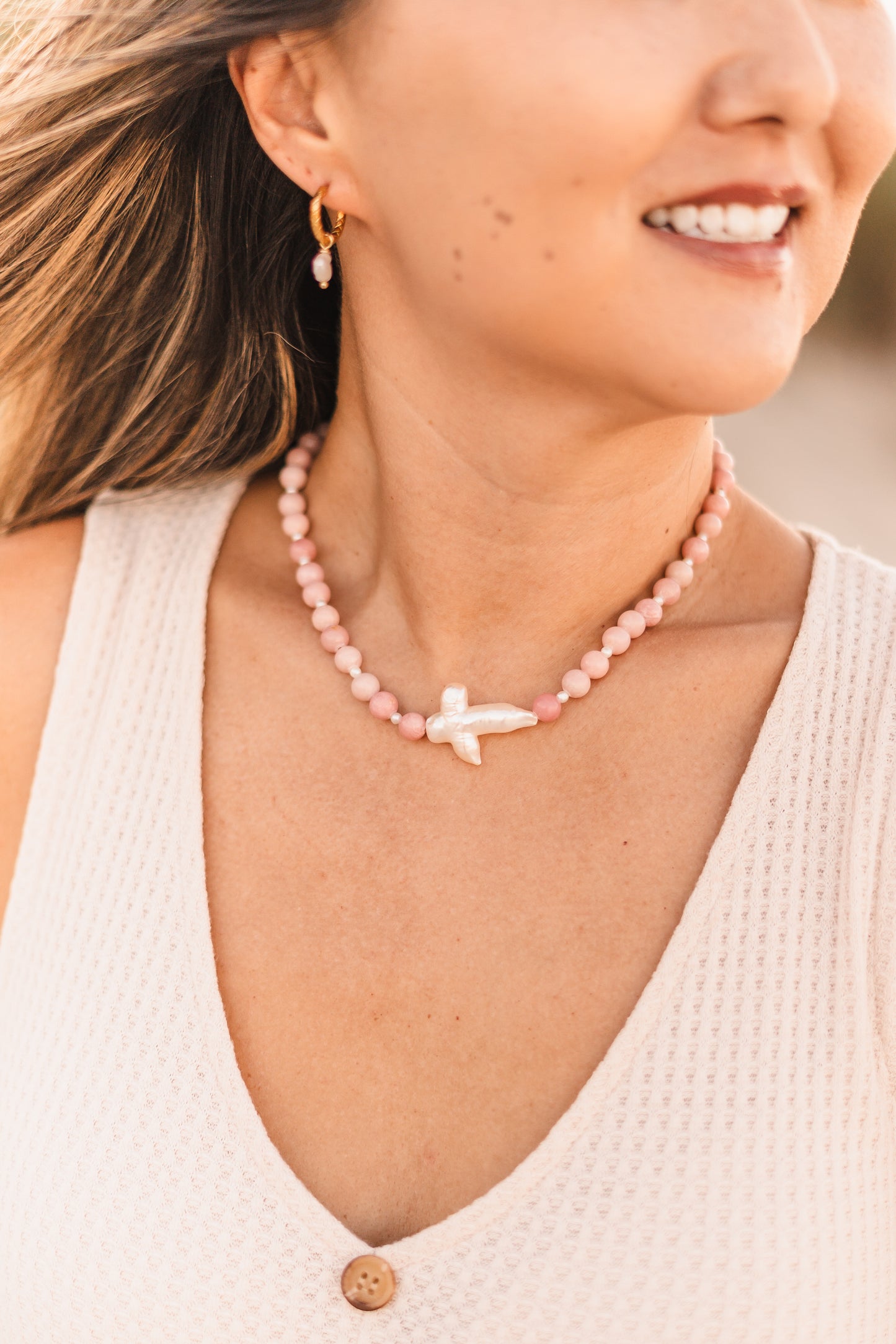 Model wearing the Blair necklace featuring pink stabilized opal beads, freshwater pearl spacers, and a freshwater pearl cross pendant on waterproof 18k Gold PVD stainless steel components.