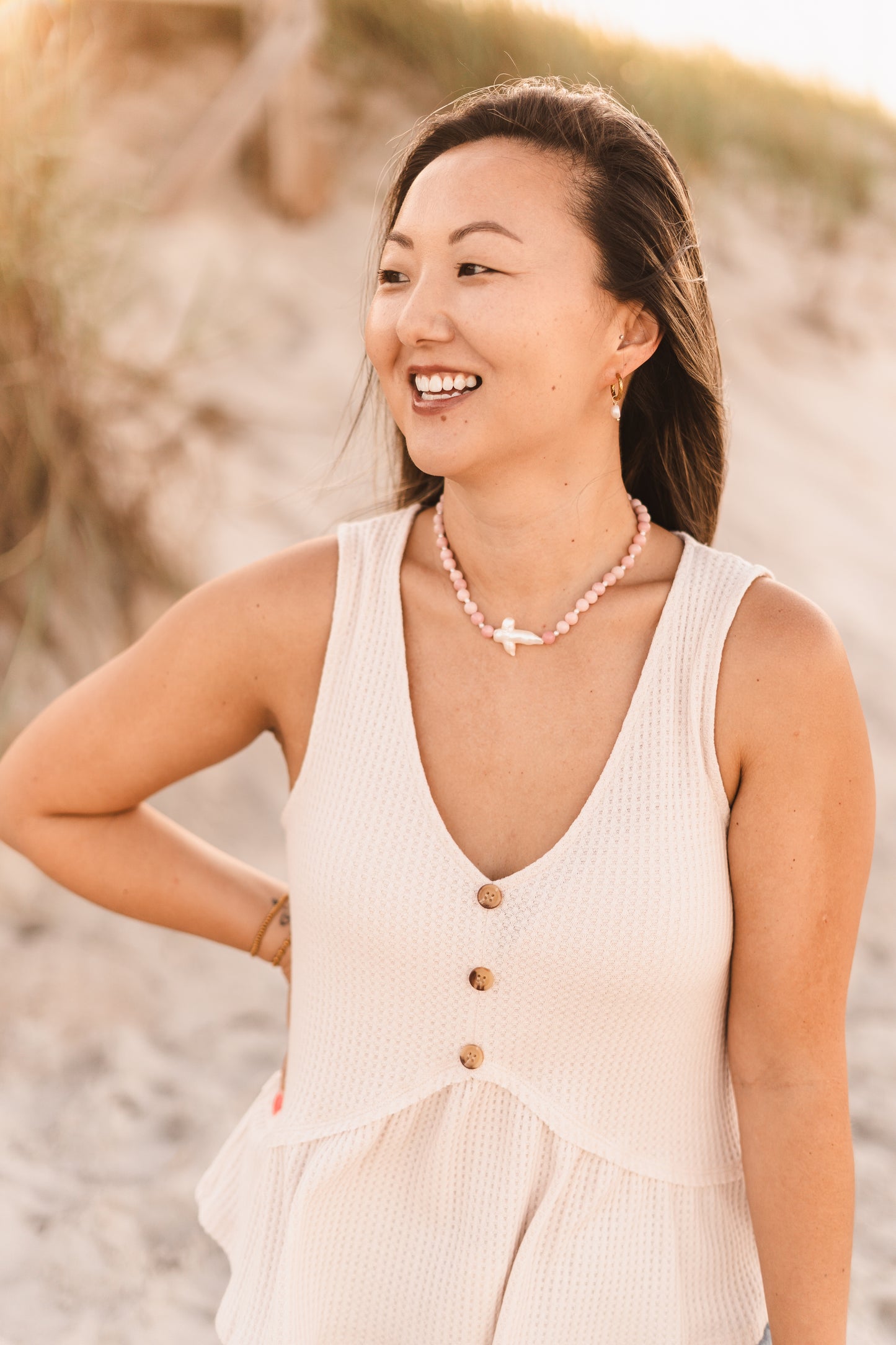 Model wearing the Blair necklace featuring pink stabilized opal beads, freshwater pearl spacers, and a freshwater pearl cross pendant on waterproof 18k Gold PVD stainless steel components.